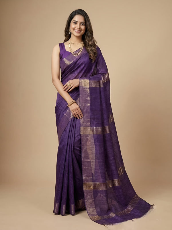 Woman wearing a purple saree with gold patterns on a beige background