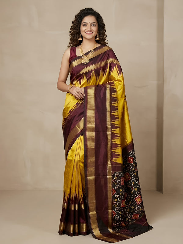 Woman wearing a yellow and brown saree with a patterned border against a beige background
