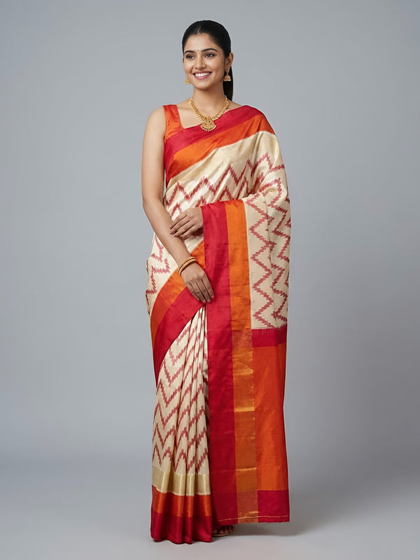 Woman wearing a red and beige saree with a gray background