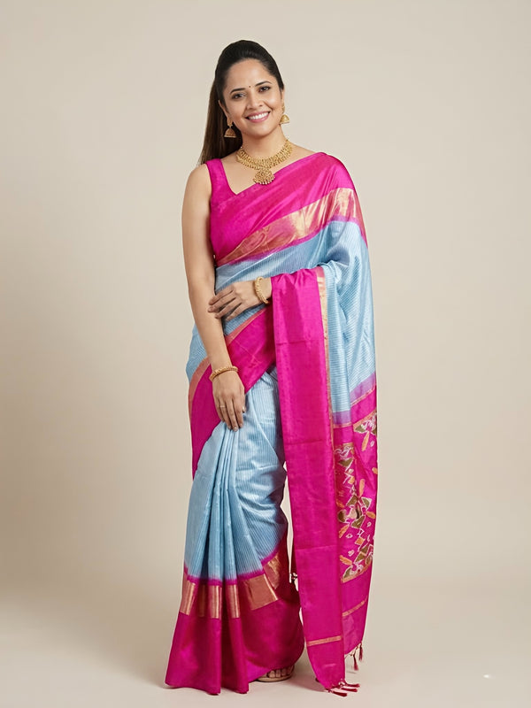 Woman wearing a pink and blue saree with a beige background