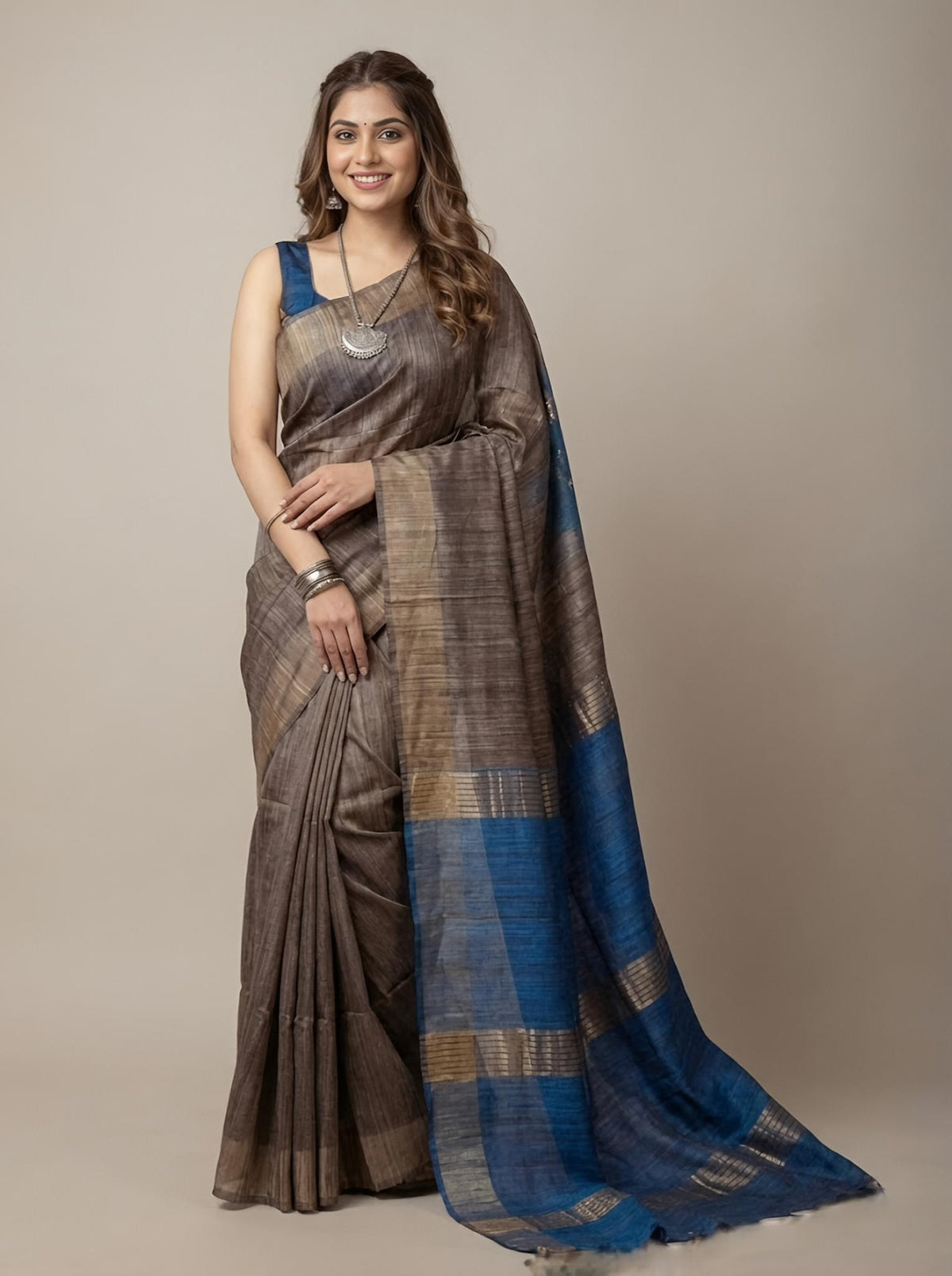 Woman wearing a saree with blue and brown patterns on a plain background