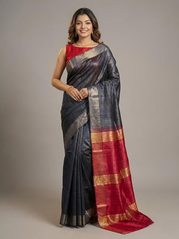 Woman wearing a traditional saree with a red and black pattern on a plain background