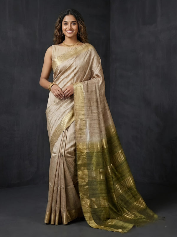 Woman wearing a beige and green saree against a dark background