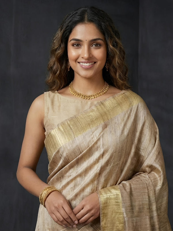 Woman wearing a traditional saree with gold accents against a dark background