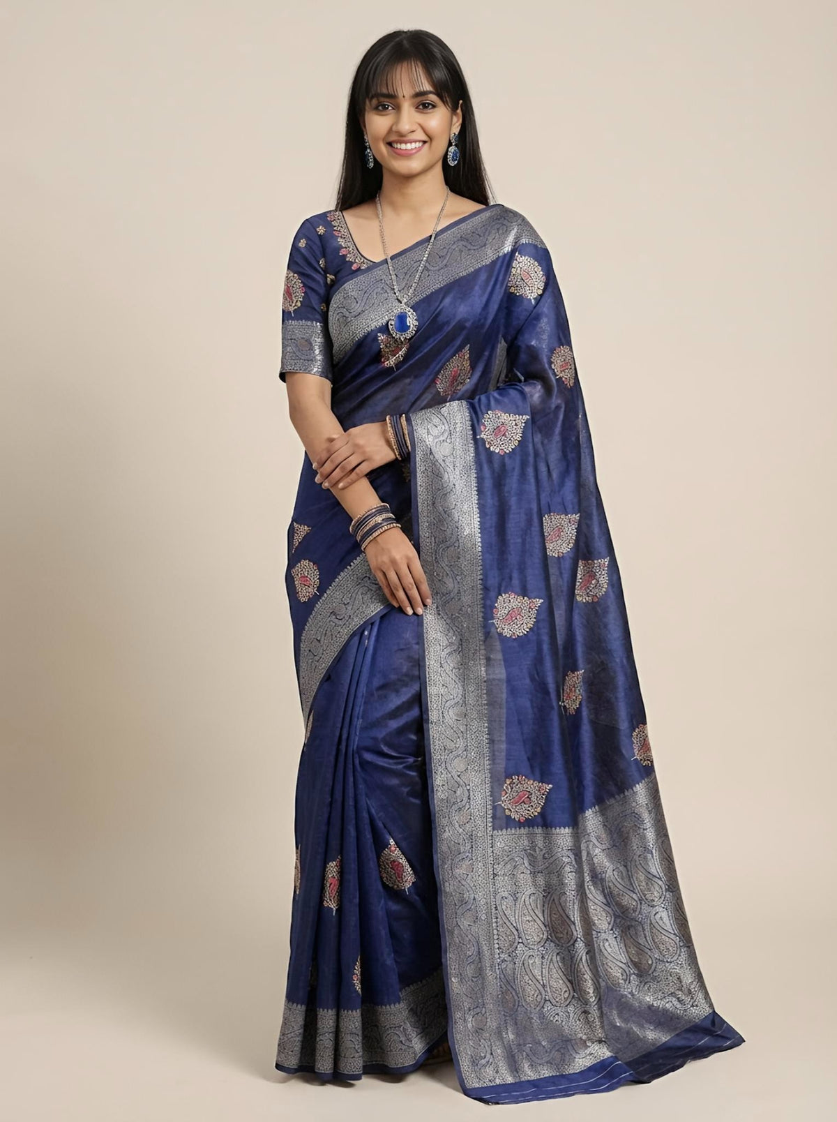 Woman wearing a blue and gray saree with a beige background