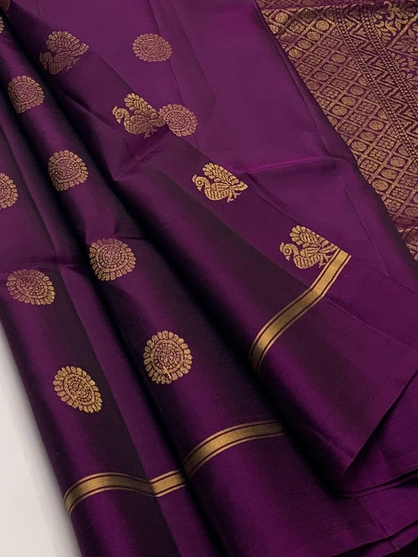 A deep purple silk saree with gold zari motifs and borders, draped elegantly to showcase its pattern and texture.