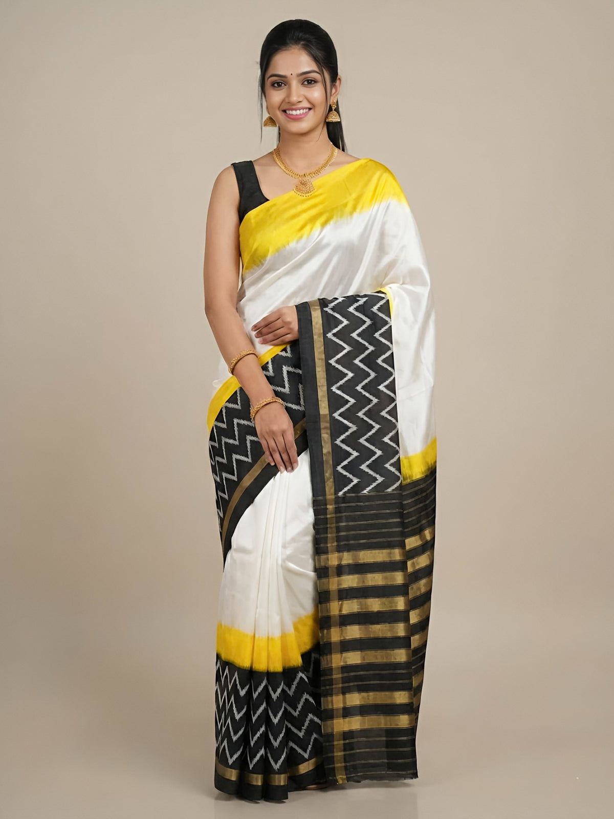 Woman wearing a white saree with black and yellow patterns on a beige background
